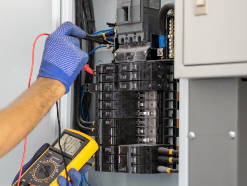 An electrician checking an electrical panel